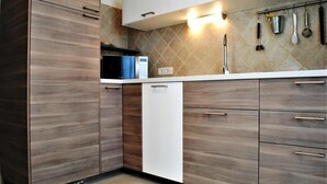 Eine moderne Küche mit Holzschränken, einem weißen Geschirrspüler und einer gefliesten Rückwand.