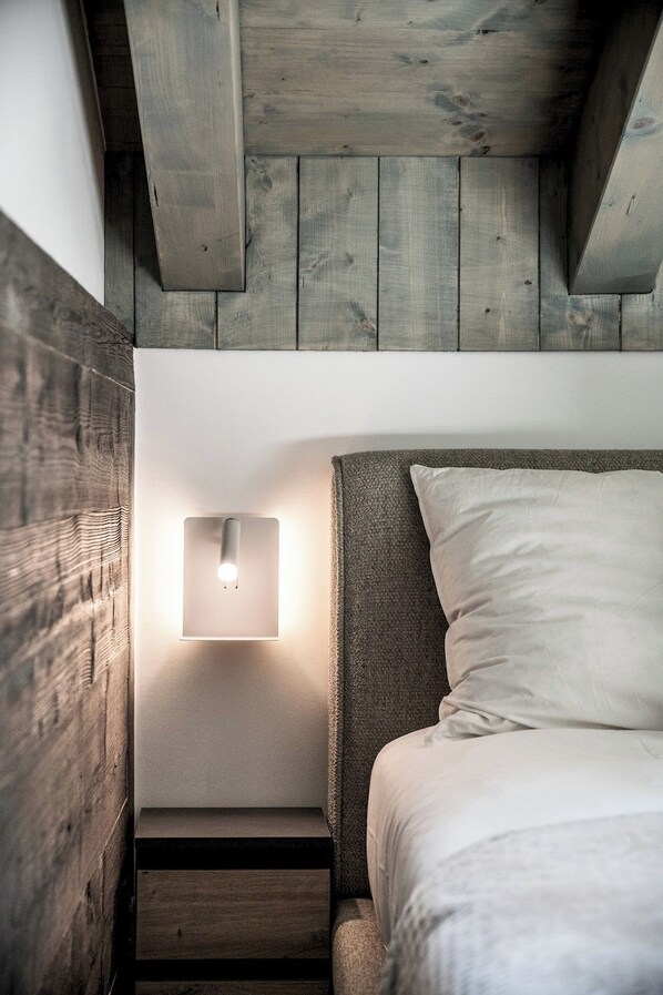 A bedroom with a bed, a nightstand, and a wall-mounted light fixture.