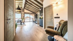 A spacious interior with a wooden ceiling, a dining area, and a seating area with a sofa and ottoman.