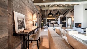 A modern living room with a wooden wall, a sofa, a dining table, and pendant lights.