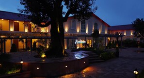 A hotel with a large tree in the courtyard, a sign reading "Radisson," and a well-lit walkway. - Radisson Resort Mount Abu (Mount Abu)