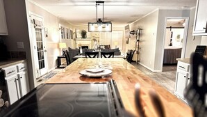 A kitchen with a central island, a dining area with a chandelier, and a hallway leading to another room. - 4BD | 3BTH | Pool | HotTub | Games |5Miles to I-95 (Elloree)