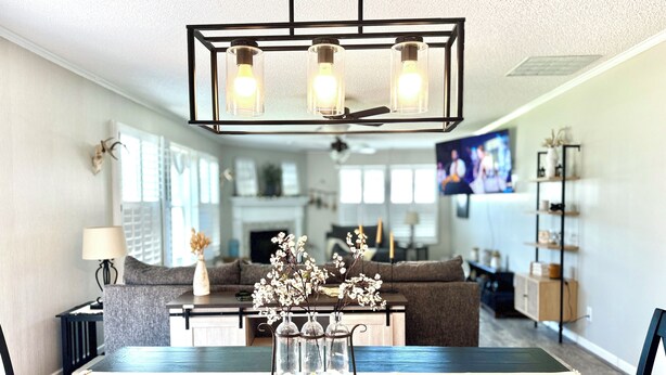 A dining area with a rectangular table, chairs, a chandelier, and a vase with flowers. - 4BD | 3BTH | Pool | HotTub | Games |5Miles to I-95 (Elloree)