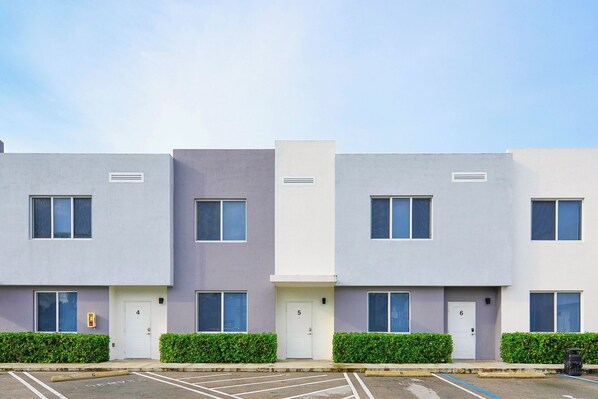 A row of modern apartment buildings with uniform window designs and door numbers. - Contemporary Townhouse Close to Design District (North Miami Beach)