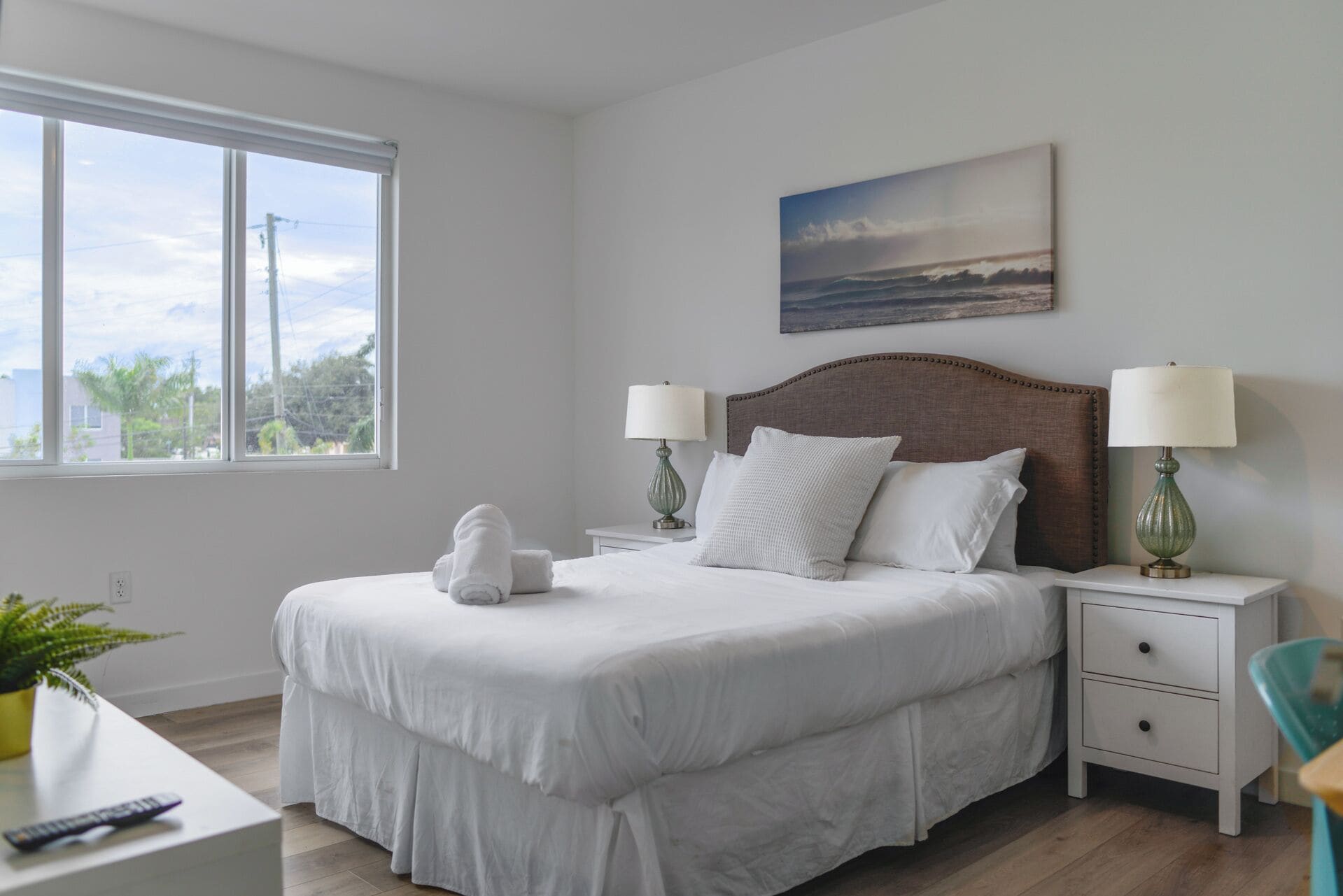 Una camera da letto ordinata con un letto grande, due comodini con lampade, una vista dalla finestra e un quadro appeso al muro.