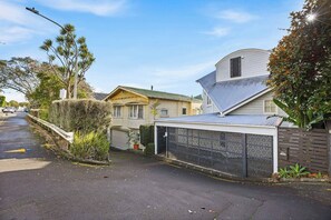 A residential street with houses, a gated driveway, and a street lamp.