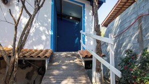 A wooden staircase leading to a blue door, surrounded by trees and a tiled roof. - Ref gio Pet-friendly c Lareira Garagem e Wi-fi (Santana de Parnaiba)