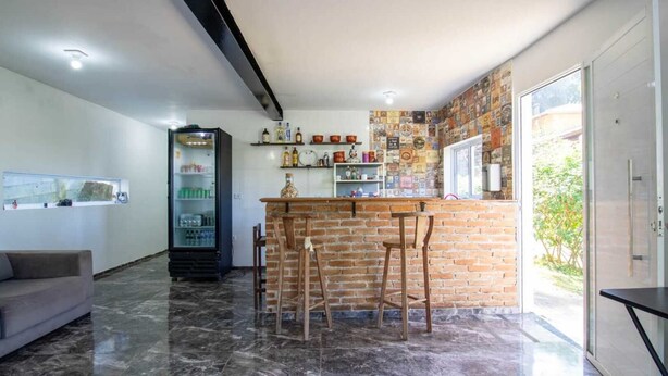 A modern kitchen with a brick island, bar stools, and a refrigerator. - Ref gio Pet-friendly c Lareira Garagem e Wi-fi (Santana de Parnaiba)