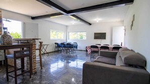 A spacious living area with a dining table set for six, a sofa, and a kitchen area with a stone wall and a large window. - Ref gio Pet-friendly c Lareira Garagem e Wi-fi (Santana de Parnaiba)