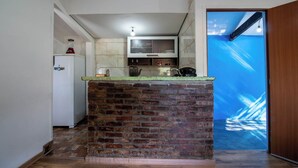 A kitchen with a brick island, a white refrigerator, a microwave, and a television above the counter. - Ref gio Pet-friendly c Lareira Garagem e Wi-fi (Santana de Parnaiba)