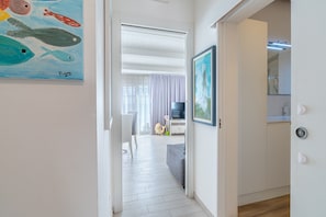 Ein Flur führt zu einem Wohnbereich mit einem Bild von Fischen, einem Fernseher und einem Sofa.