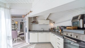 Une cuisine moderne avec des meubles blancs, un four encastré et un coin repas comprenant une table et des chaises.