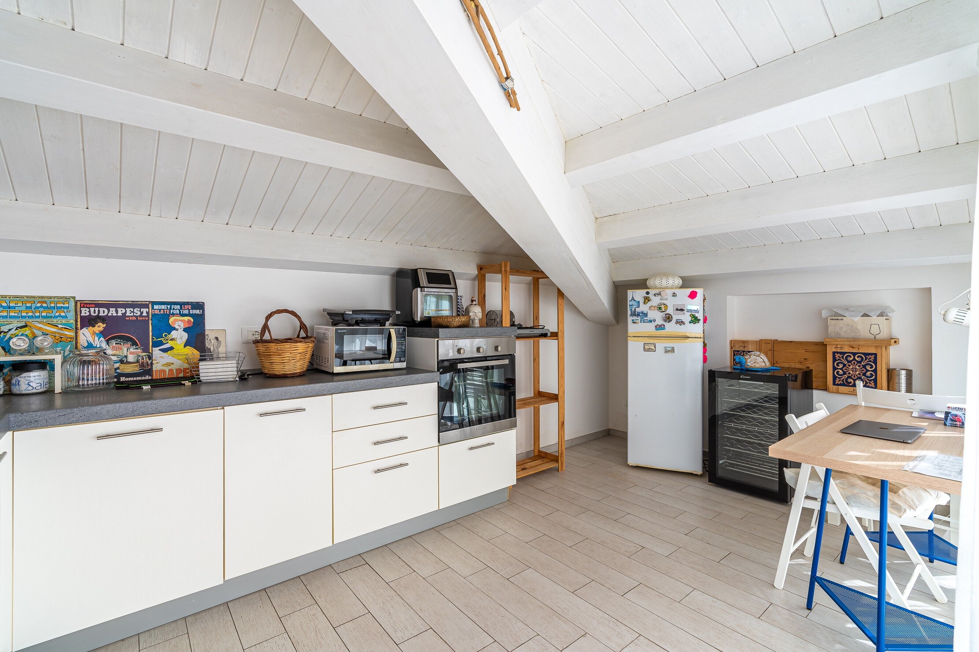 Eine moderne Küche mit weißen Schränken, einer Mikrowelle, einem Backofen und einem Kühlschrank.