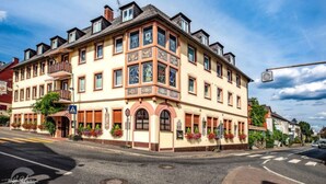 A multi-story building with a corner facade, large windows, and a balcony. - Family-run hotel with a central location (Rüdesheim am Rhein)