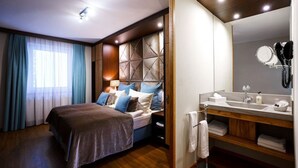 A modern hotel room with a large bed, a vanity with a mirror, and a wooden headboard. - Family-run hotel with a central location (Rüdesheim am Rhein)