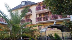 A multi-story building with balconies adorned with flowers, outdoor seating, and a covered area. - Family-run hotel with a central location (Rüdesheim am Rhein)