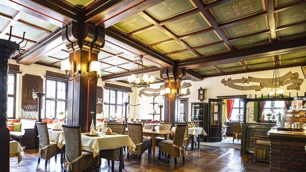 A spacious dining area with wooden flooring and high ceilings, featuring tables and chairs arranged for dining. - Family-run hotel with a central location (Rüdesheim am Rhein)