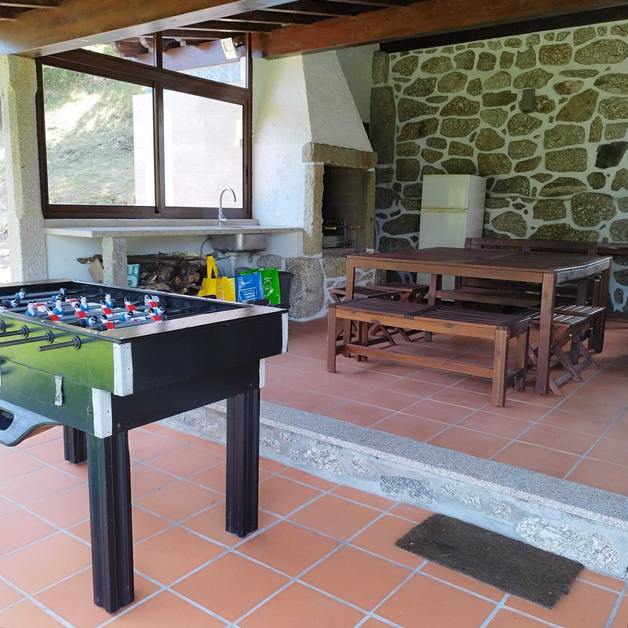 Spazio ricreativo interno con tavolo da calcio, parete in pietra e finestra.