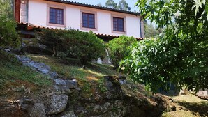 Une maison à deux étages avec un mur en pierre et un jardin.