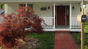 Une maison à deux étages avec un porche à l’avant, une boîte aux lettres et le numéro « 125 » sur la porte.