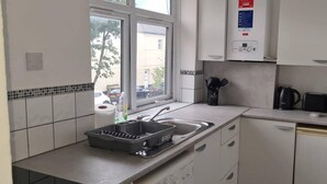 Una cocina moderna con armarios blancos, horno empotrado, microondas y un lavamanos.