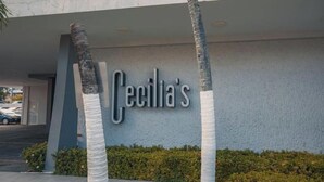 Un bâtiment sur lequel on peut lire l’inscription « Cecilia’s », et des palmiers enveloppés d’un tissu blanc.