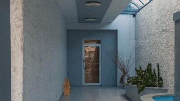 Un couloir donnant sur un espace piscine, avec un plafond en verre et une porte au bout.