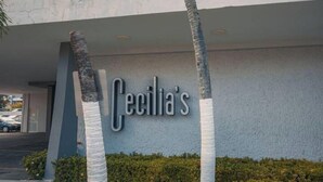 A building with a sign reading "Cecilia's" and palm trees wrapped in white material. - Sofia’s Beach Apartment (Carolina)