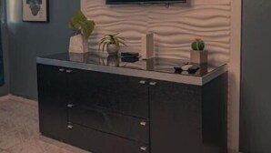 A modern living room with a flat-screen TV mounted on a textured wall, a dark-colored entertainment unit, and a potted plant. - Sofia’s Beach Apartment (Carolina)