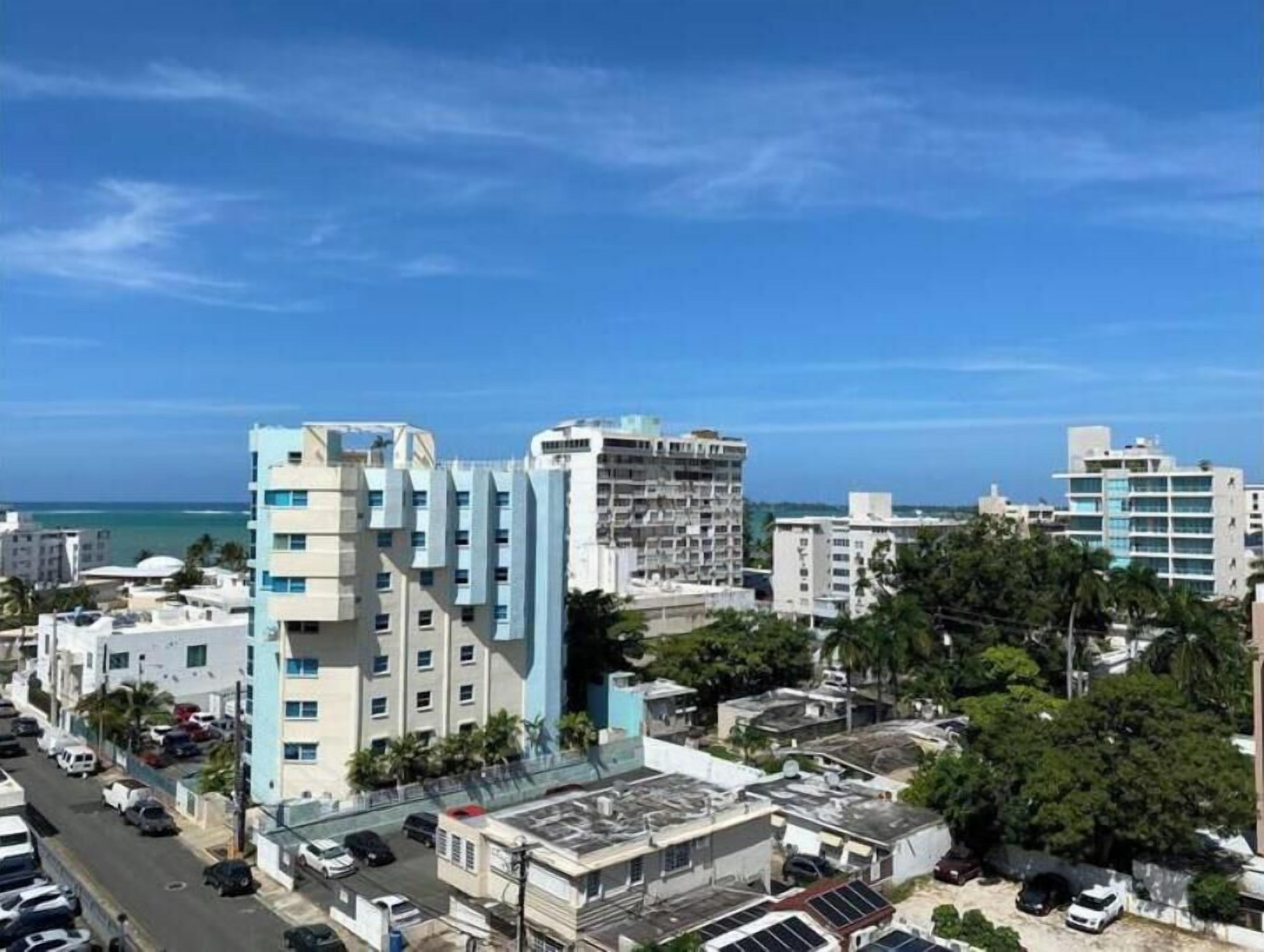 A cityscape with modern buildings, a clear blue sky, and a view of the ocean.