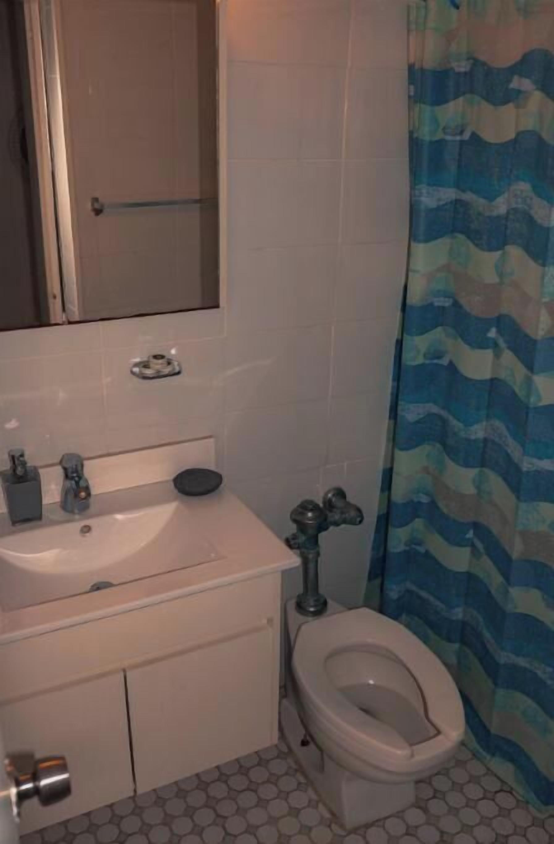 A bathroom with a toilet, sink, and mirror.