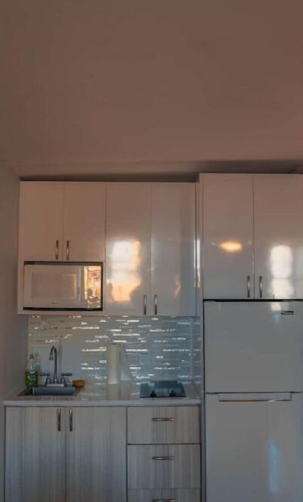 A modern kitchen with stainless steel appliances, a built-in oven, and a microwave. - Jessy’s Beach Apartment (Carolina)