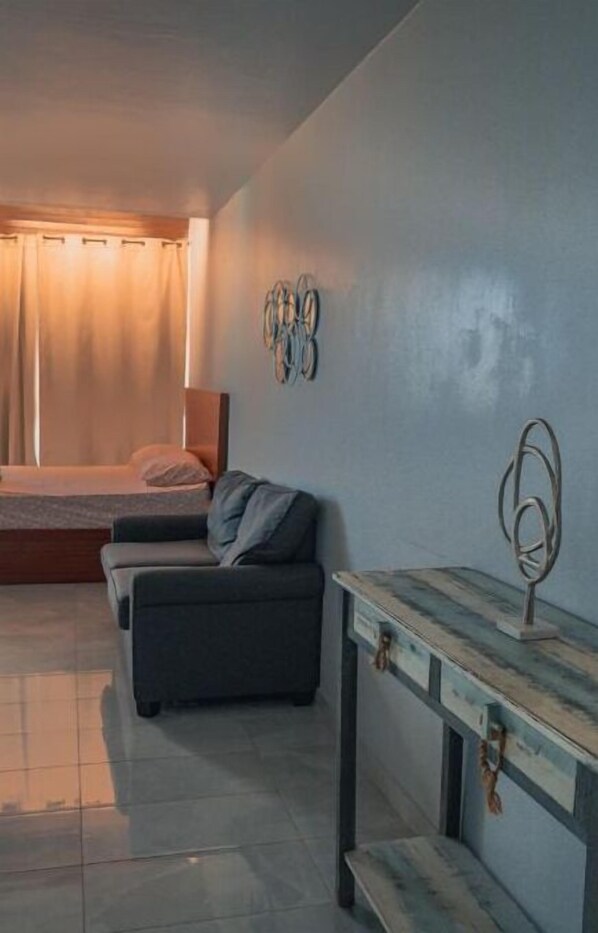 Une chambre moderne avec un lit, un canapé, une petite table et un luminaire fixé au mur.