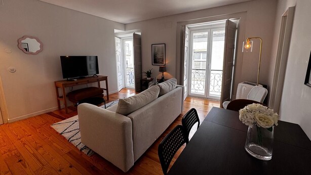 A living room with a sofa, TV, and a dining table with chairs.