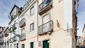 A row of buildings with balconies, green doors, and a cobblestone street.