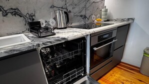 A modern kitchen with a built-in dishwasher, stainless steel appliances, and a marble backsplash.