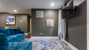 Een moderne woonkamer met een blauwe bank, een kamerkleed met patroon en twee decoratieve wandpanelen.
