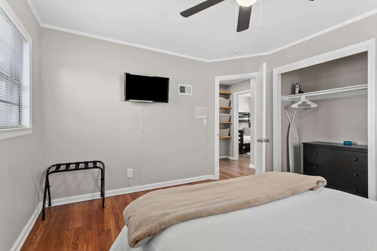 A bedroom with a bed, a television, a closet, and a window.