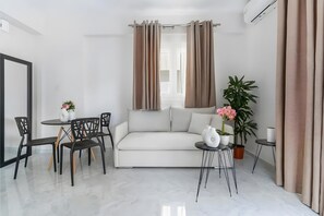 Uma sala moderna com um sofá, uma mesa de jantar com cadeiras, uma mesinha lateral e um vaso de planta.