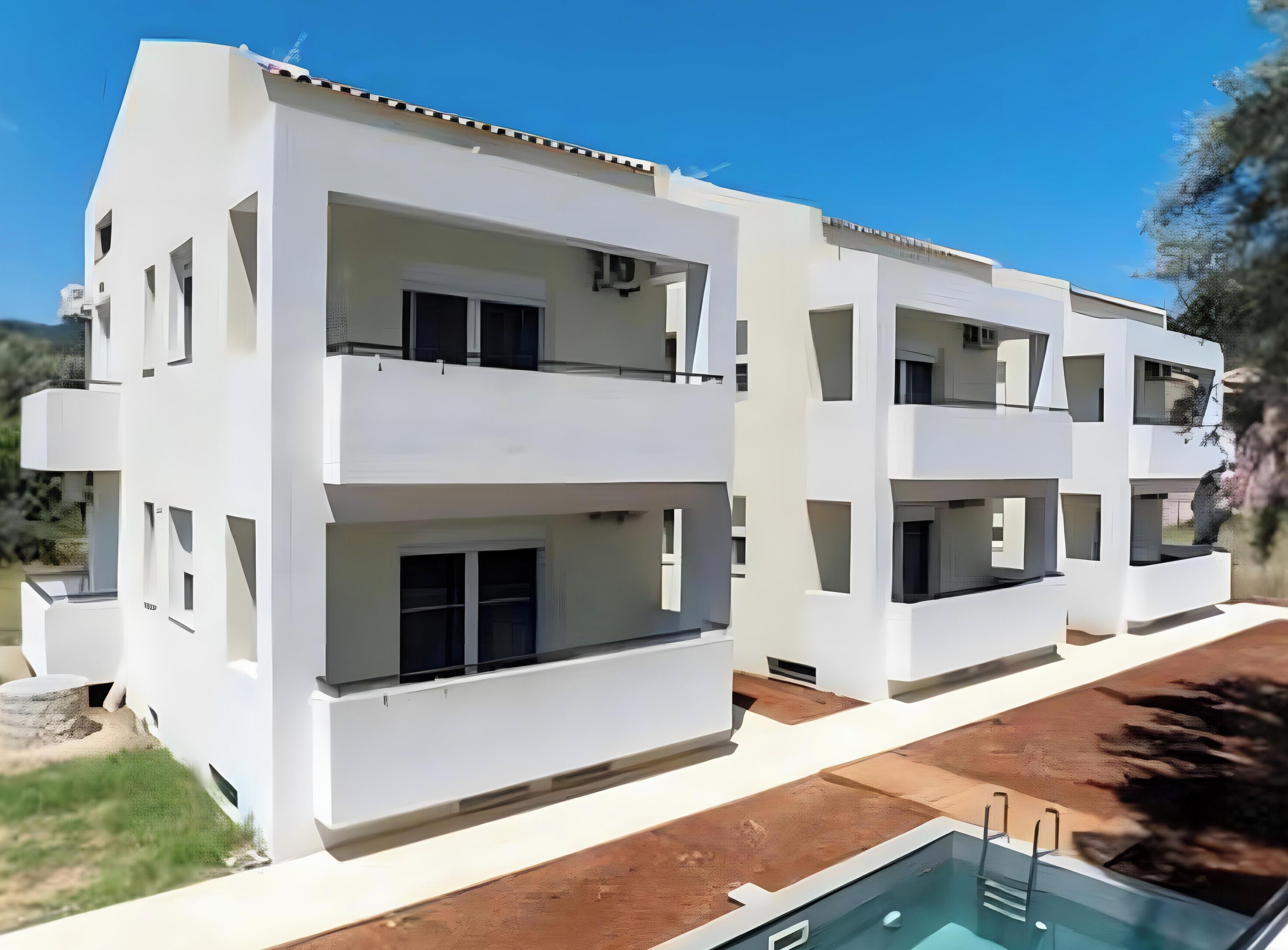Un immeuble moderne à plusieurs étages, doté de balcons, d’une piscine et surplombant un ciel dégagé.