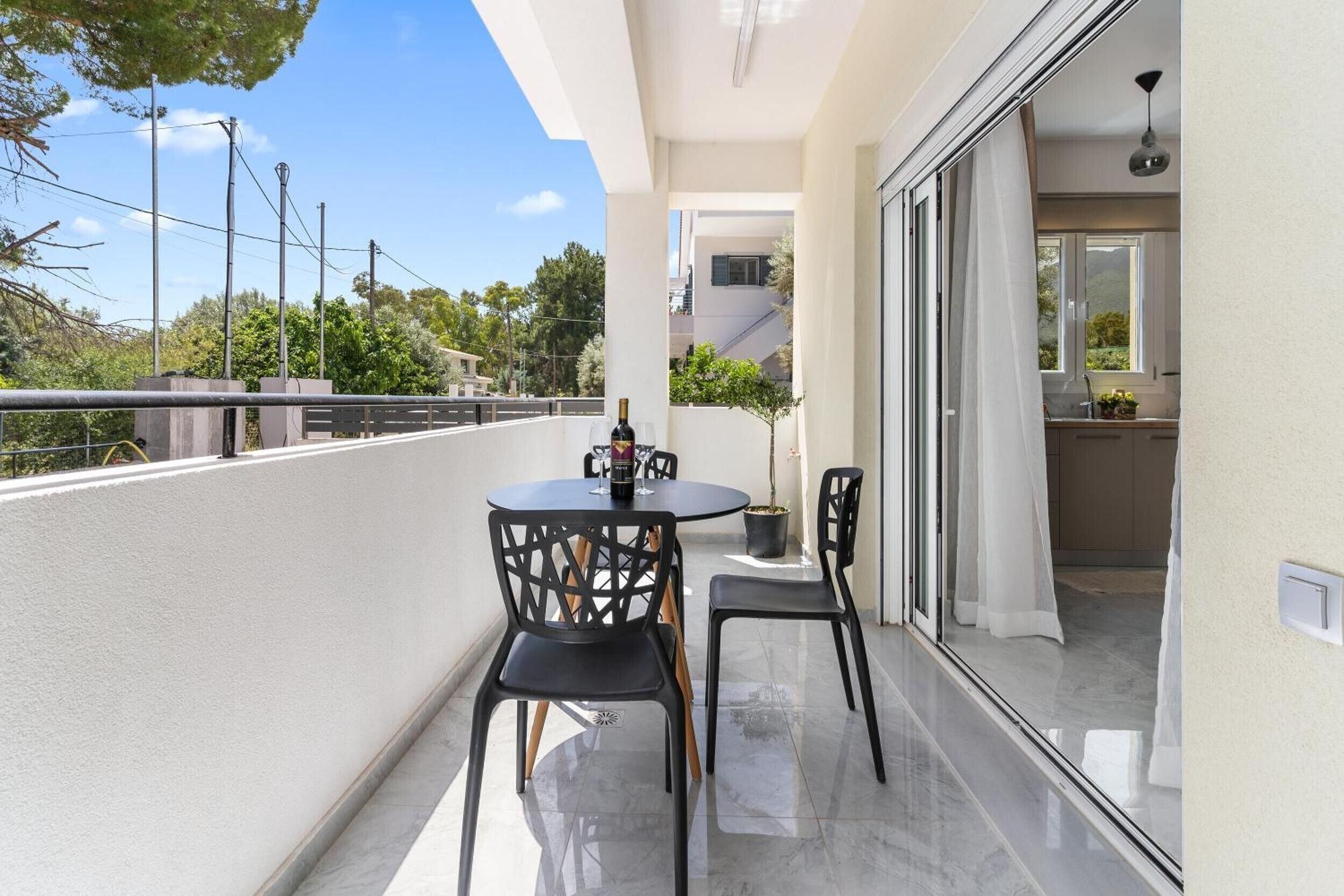 A balcony with a table and chairs, a potted plant, and a view of the surrounding area.