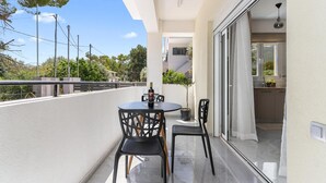 A balcony with a table and chairs, a potted plant, and a view of the surrounding area.