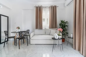 Un salon moderne comprenant un canapé, une table à manger, des chaises, une plante en pot et une petite table d’appoint.