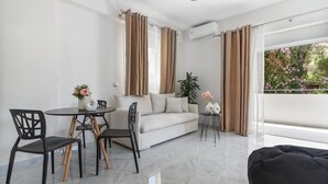 A modern living room with a sofa, dining table, chairs, and a small side table with decorative items.
