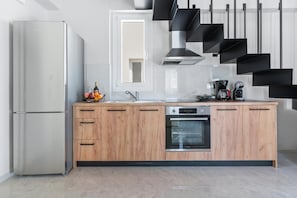 Een moderne keuken met een koelkast, oven en houten kasten.