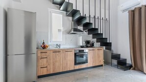 Una cocina moderna con un refrigerador de acero inoxidable, armarios de madera, horno integrado y una escalera negra original.