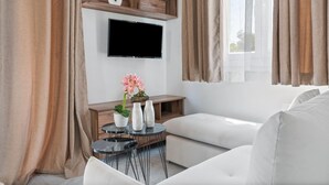 Una sala de estar moderna con un televisor de pantalla plana, una mesita con jarrones y un sofá.