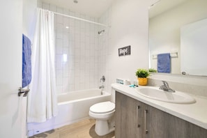 Un bagno moderno con vasca, water e lavandino. Un cartello al muro recita 'Hope'.
