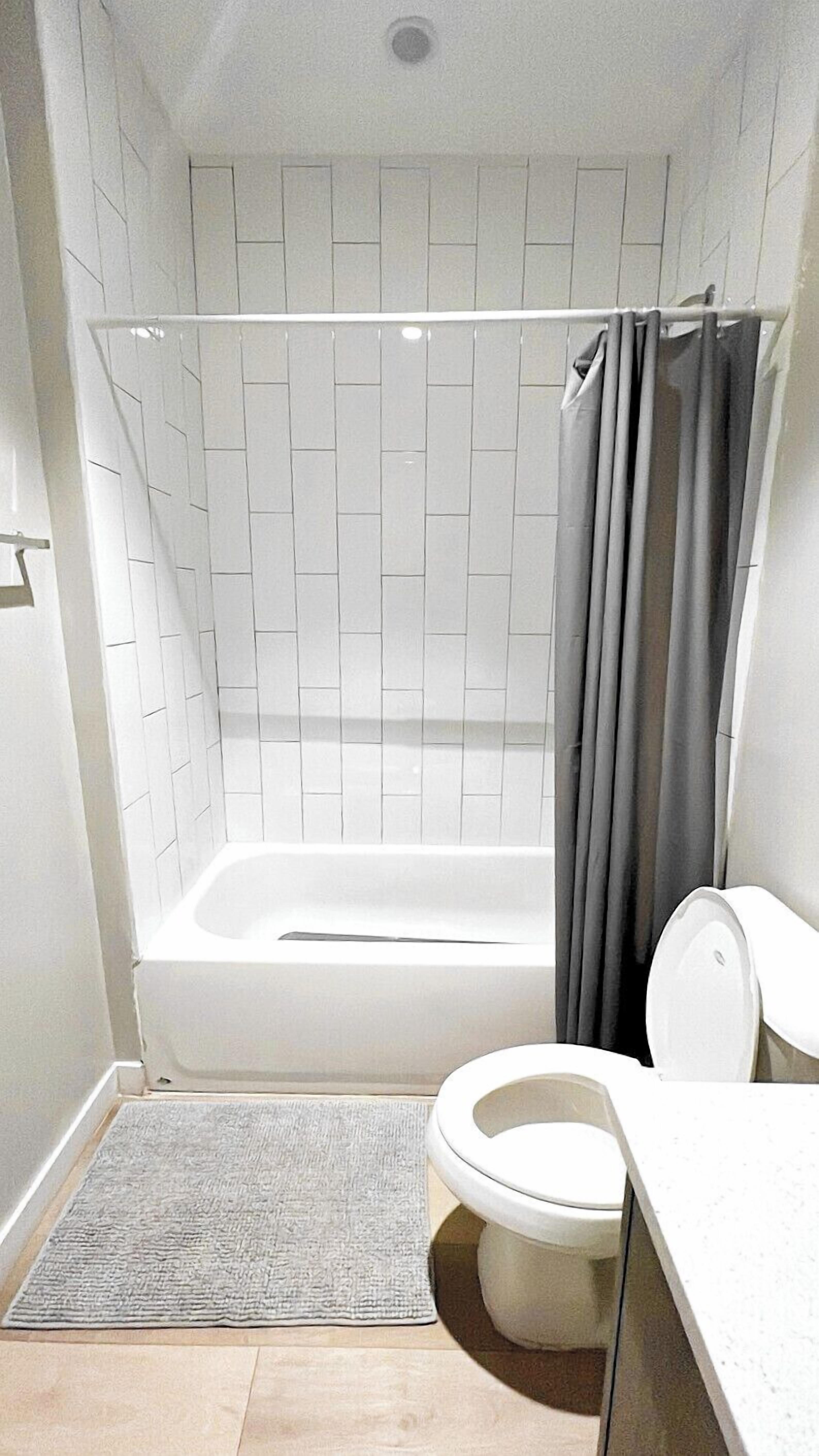 A bathroom with a white bathtub, a toilet, and a shower curtain.