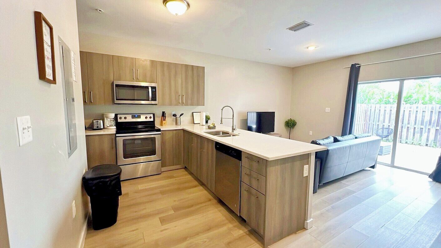 A modern kitchen with wooden cabinets, stainless steel appliances, and a large island.